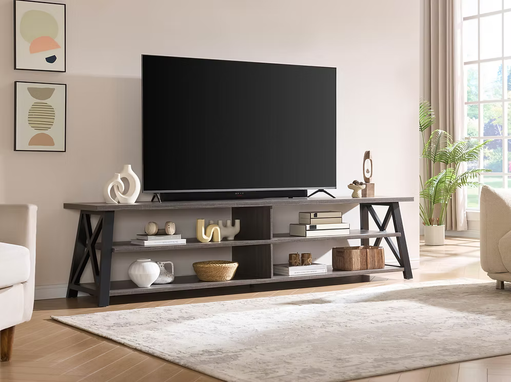 Lexa 91 inch extra large TV stand console in black and distressed grey finish with open shelving and side X-frame accents displaying a large television