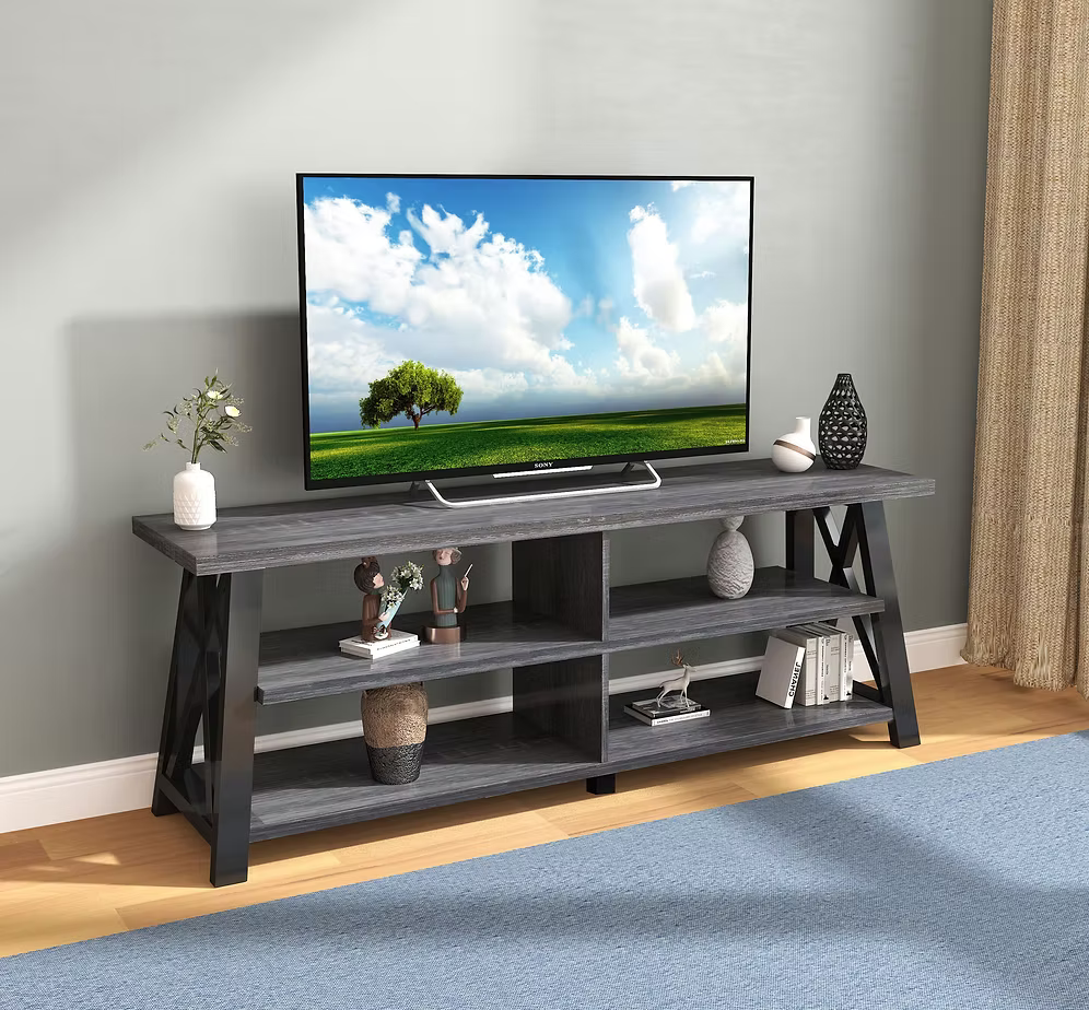 Odda 71 inch modern TV stand in a distressed grey finish with rustic open shelves and black geometric X-frame side panels supporting a flat screen television