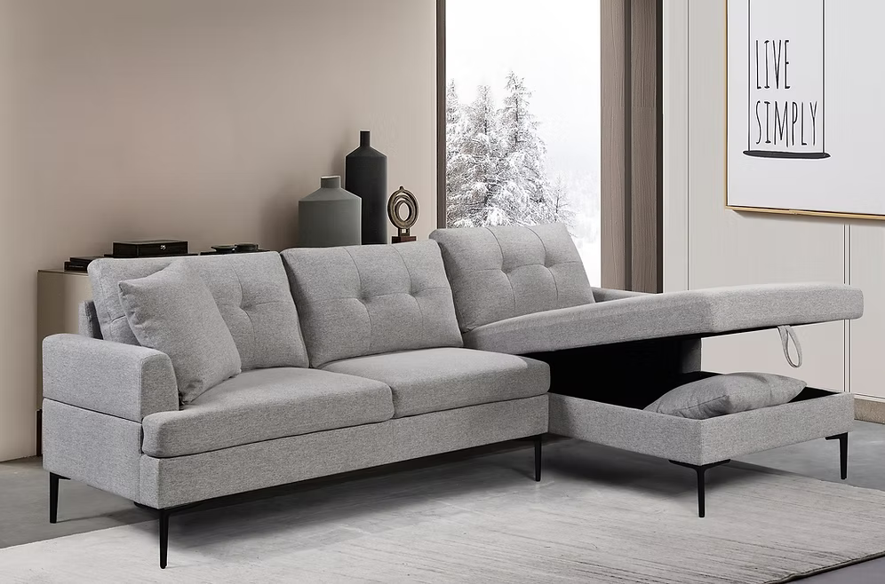 Monti modern right-hand facing sectional sofa bed in soft grey fabric featuring button tufted back cushions, black metal legs, and a pull-out guest bed